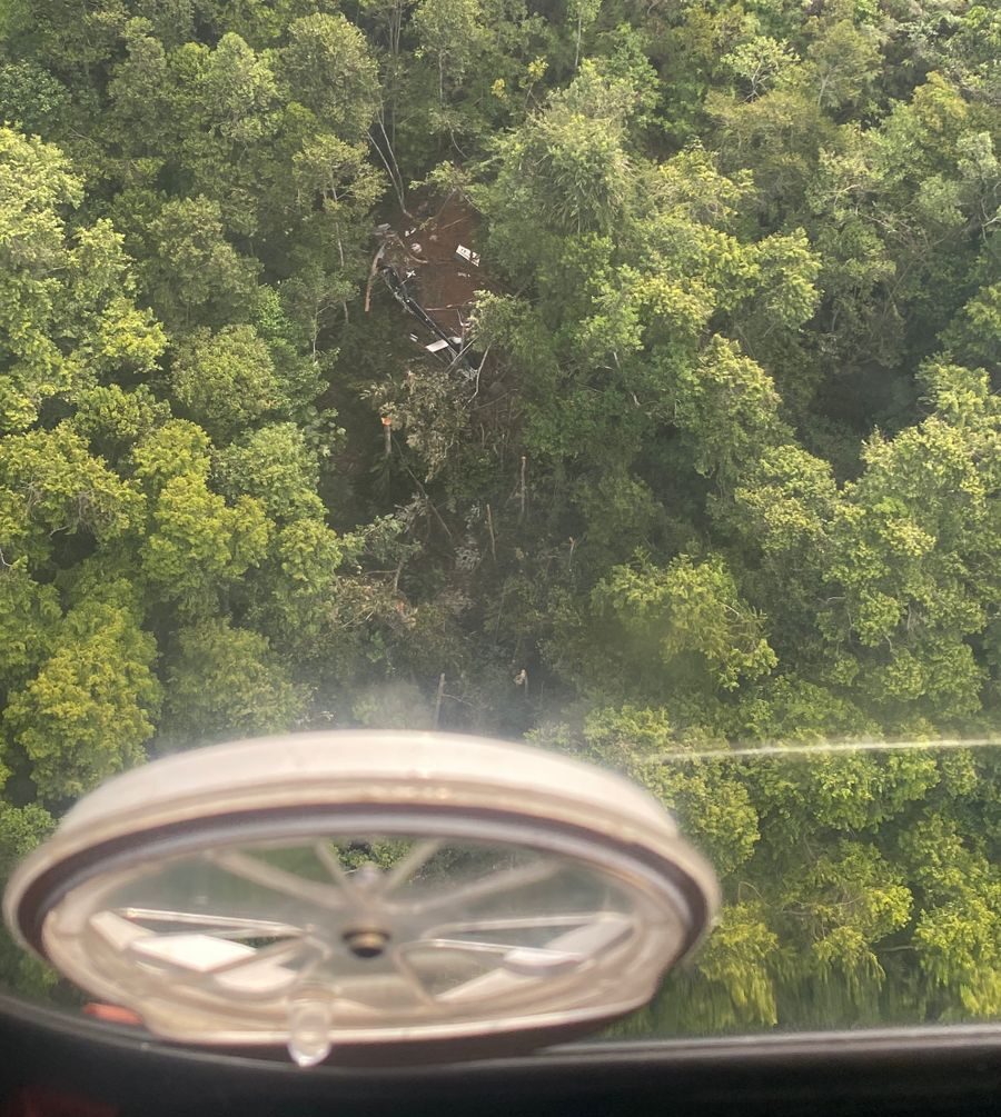 Foto udara dari jendela helikopter pencari menunjukkan area tanah cokelat terbuka di tengah hutan hijau yang sangat lebat di Kalimantan Barat, dengan puing-puing kecil pesawat terlihat.