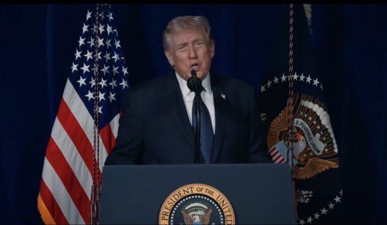residen Donald Trump memberikan pidato di podium dengan latar belakang bendera Amerika Serikat terkait krisis diplomatik Pakistan-Iran.