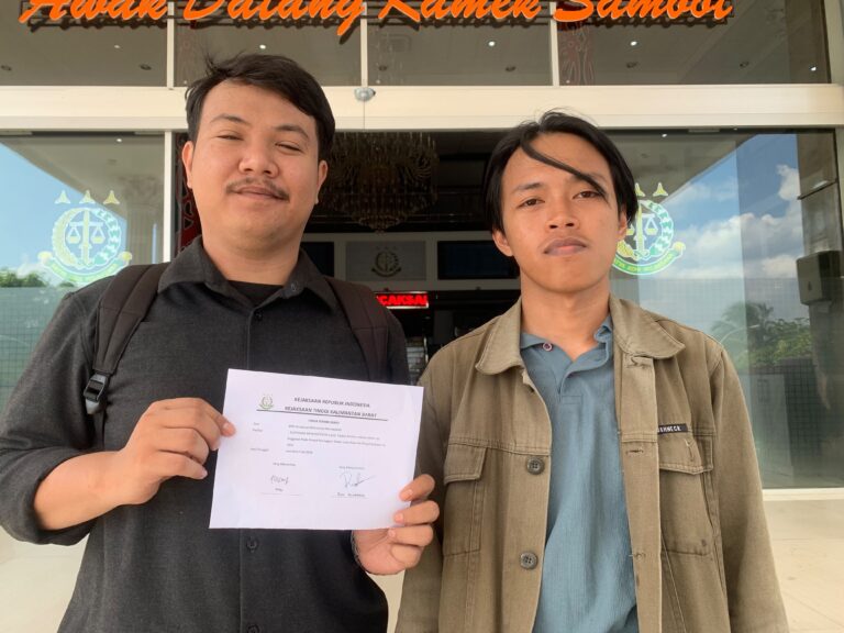 Dua perwakilan mahasiswa PRISMA menunjukkan kertas bukti tanda terima laporan di depan kantor Kejaksaan Tinggi Kalimantan Barat.