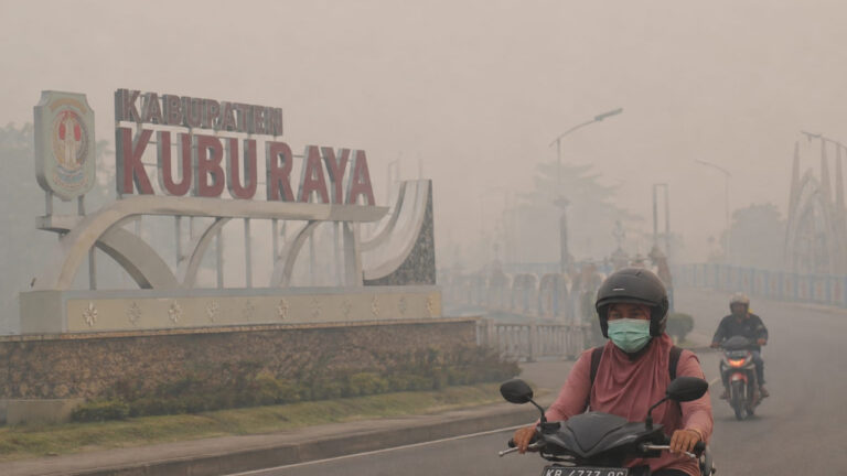 Pengendara sepeda motor mengenakan masker melintas di depan tugu Kabupaten Kubu Raya yang diselimuti kabut asap tebal pekat akibat karhutla. (Dok. HO/NusantaraPost)