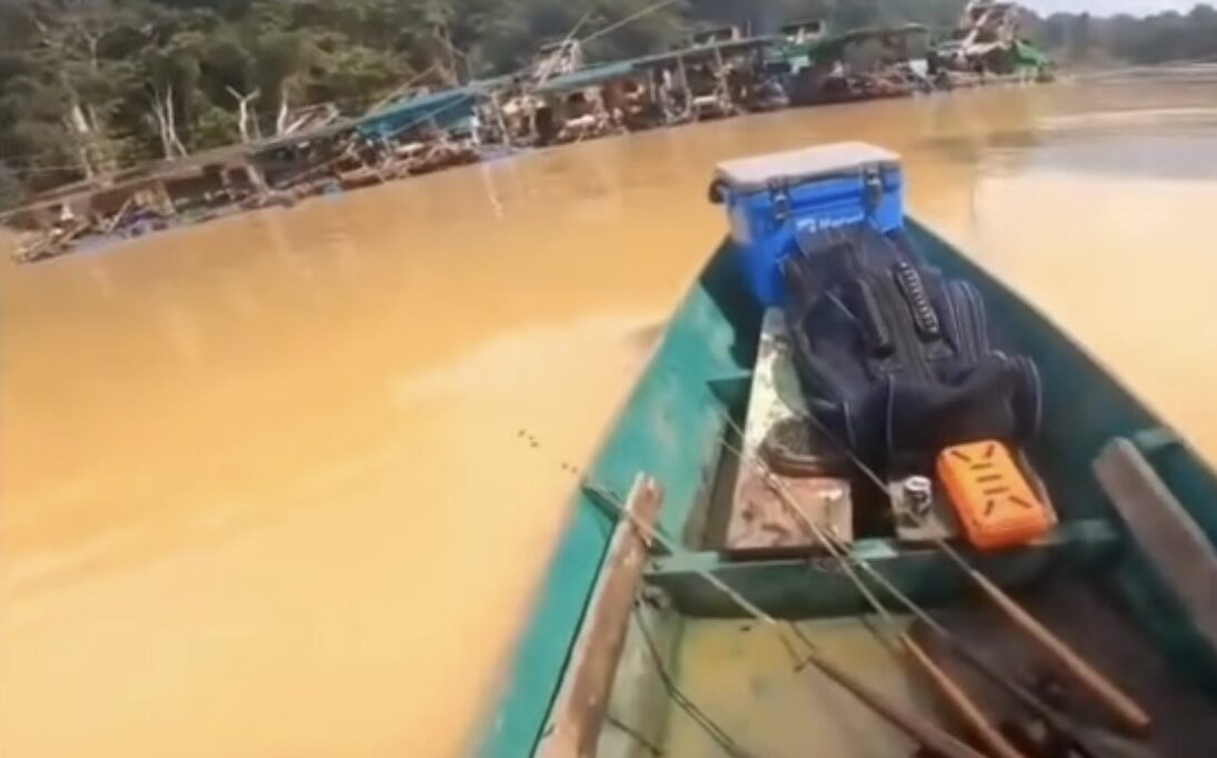 Pemandangan dari atas perahu motor melintasi air sungai yang berwarna cokelat keruh akibat aktivitas pertambangan emas tanpa izin.