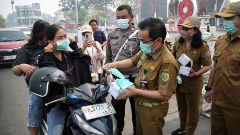 Petugas gabungan dan ASN membagikan masker gratis kepada pengendara motor di tengah kabut asap karhutla di Kalimantan Tengah. (Dok. MC Kota Palangka Raya/Usep)