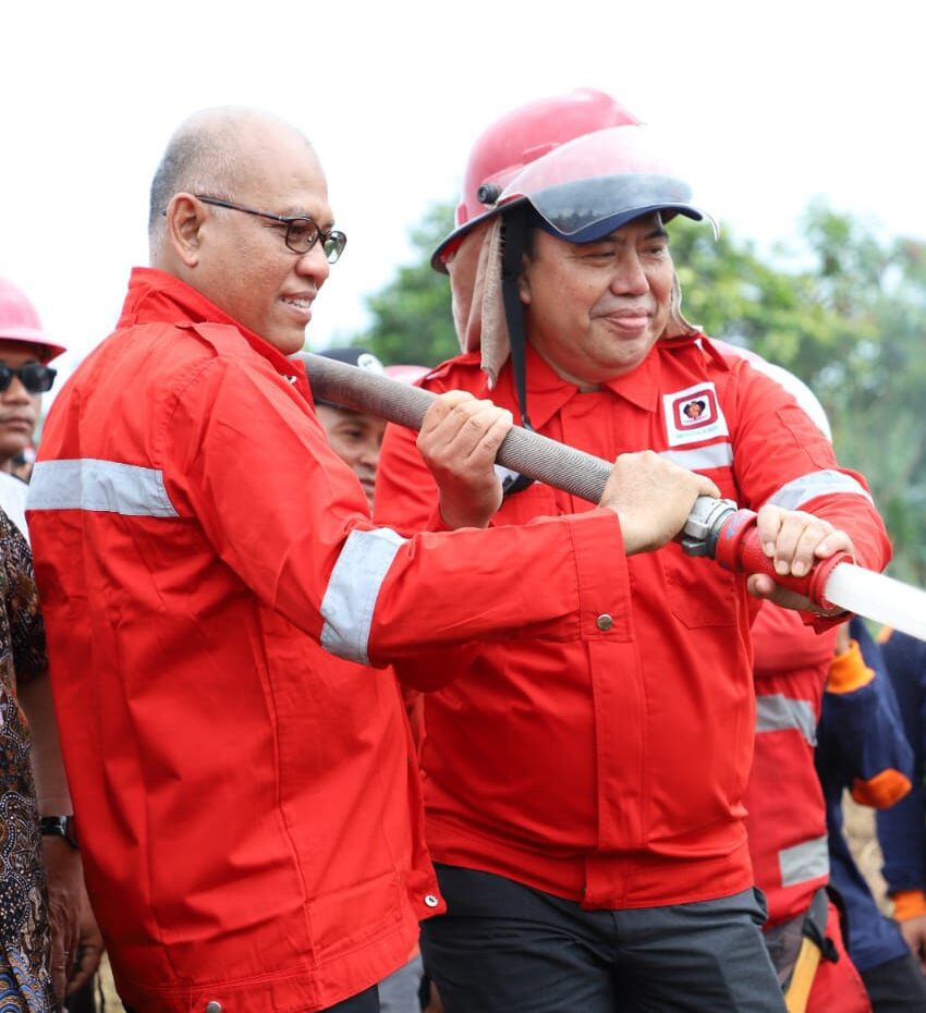 Kepala Dinas LHK Kalbar Adiyani mengenakan jaket merah seragam pemadam kebakaran bersama seorang petugas lain memegang selang air pemadam di lokasi karhutla.