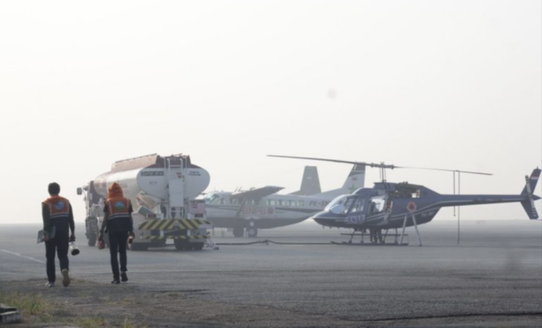 Petugas BNPB berjalan menuju helikopter dan pesawat water bombing di tengah kabut asap Kalimantan Selatan