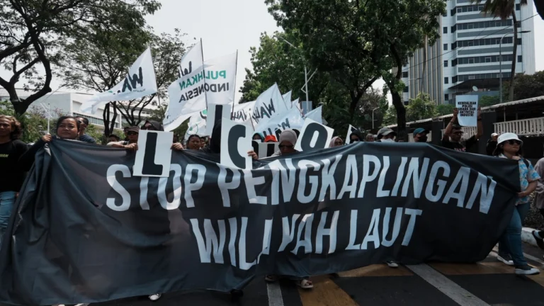 Massa aksi WALHI membentangkan spanduk hitam bertuliskan "Stop Pengkaplingan Wilayah Laut" sambil mengibarkan bendera organisasi saat menggelar aksi unjuk rasa memperingati Hari Keadilan Ekologis di Jakarta. (Dok. Walhi Nasional)