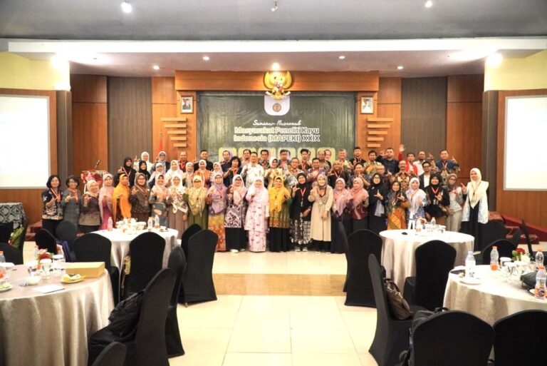 peserta seminar berfoto bersama dalam dua baris di ruang pertemuan dengan layar putih di belakangnya.