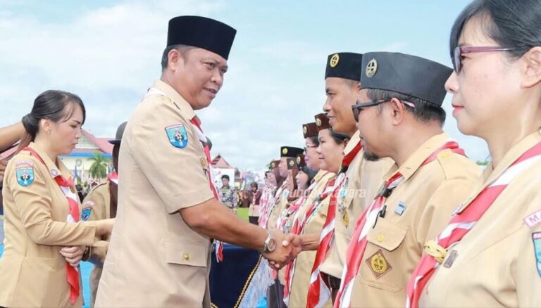 Asisten Pemprov Kaltara Sanusi mengenakan seragam Pramuka menyalami jajaran peserta.