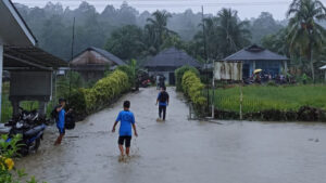 Warga berjalan menerobos genangan banjir yang merendam kawasan permukiman di Kecamatan O'o'u, Nias Selatan. (Dok. BNPB)