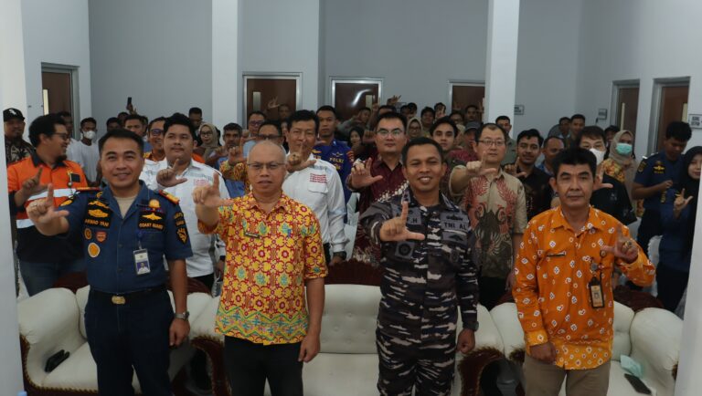 Puluhan peserta dan empat pejabat berseragam dan berbatik berfoto bersama dengan isyarat tangan huruf L di dalam ruangan.