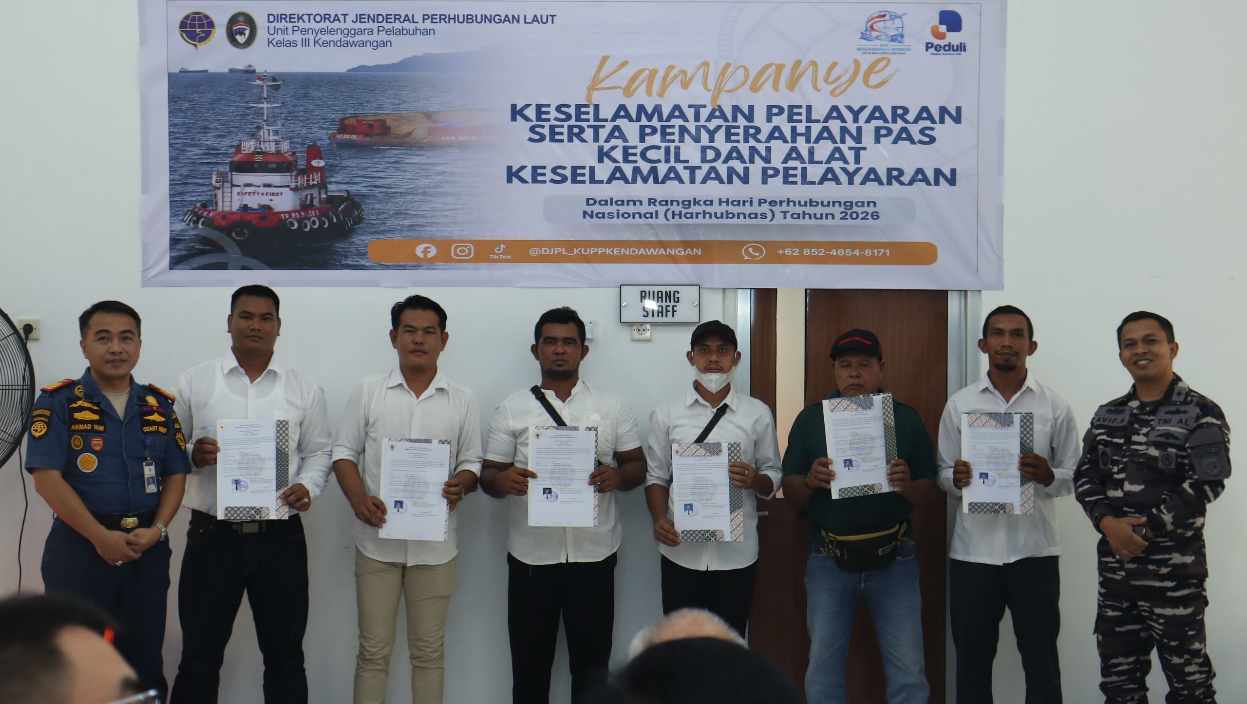 Enam penerima memegang dokumen berbingkai batik, diapit seorang petugas Coast Guard dan seorang perwira TNI AL.