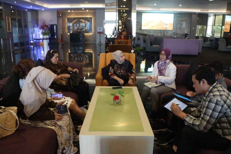 Tujuh orang duduk melingkar di sofa lobi hotel dalam rapat koordinasi persiapan IKK Awards 2026 di Balikpapan.