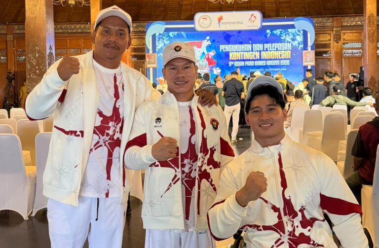 Tiga atlet berjaket putih-merah kontingen Indonesia mengepalkan tangan di depan latar acara pelepasan Asian Para Games 2026.